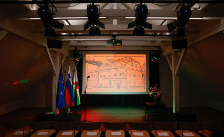 dvorana v Vodnikovi domačiji, v ozadju oder s platnom