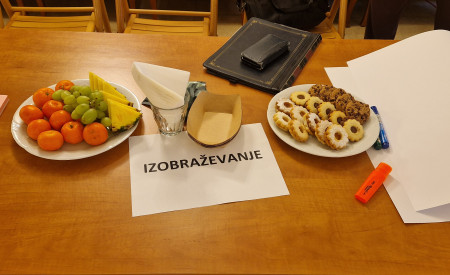 miza, na kateri sta krožnika s sadjem in piškoti ter list z napisom IZOBRAŽEVANJE
