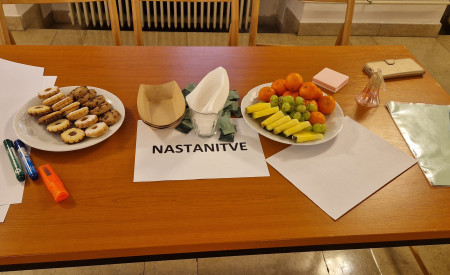 miza, na kateri sta krožnika s sadjem in piškoti ter list z napisom NASTANITVE