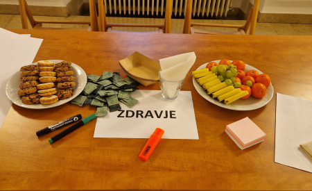 miza, na kateri sta krožnika s sadjem in piškoti ter list z napisom ZDRAVJE
