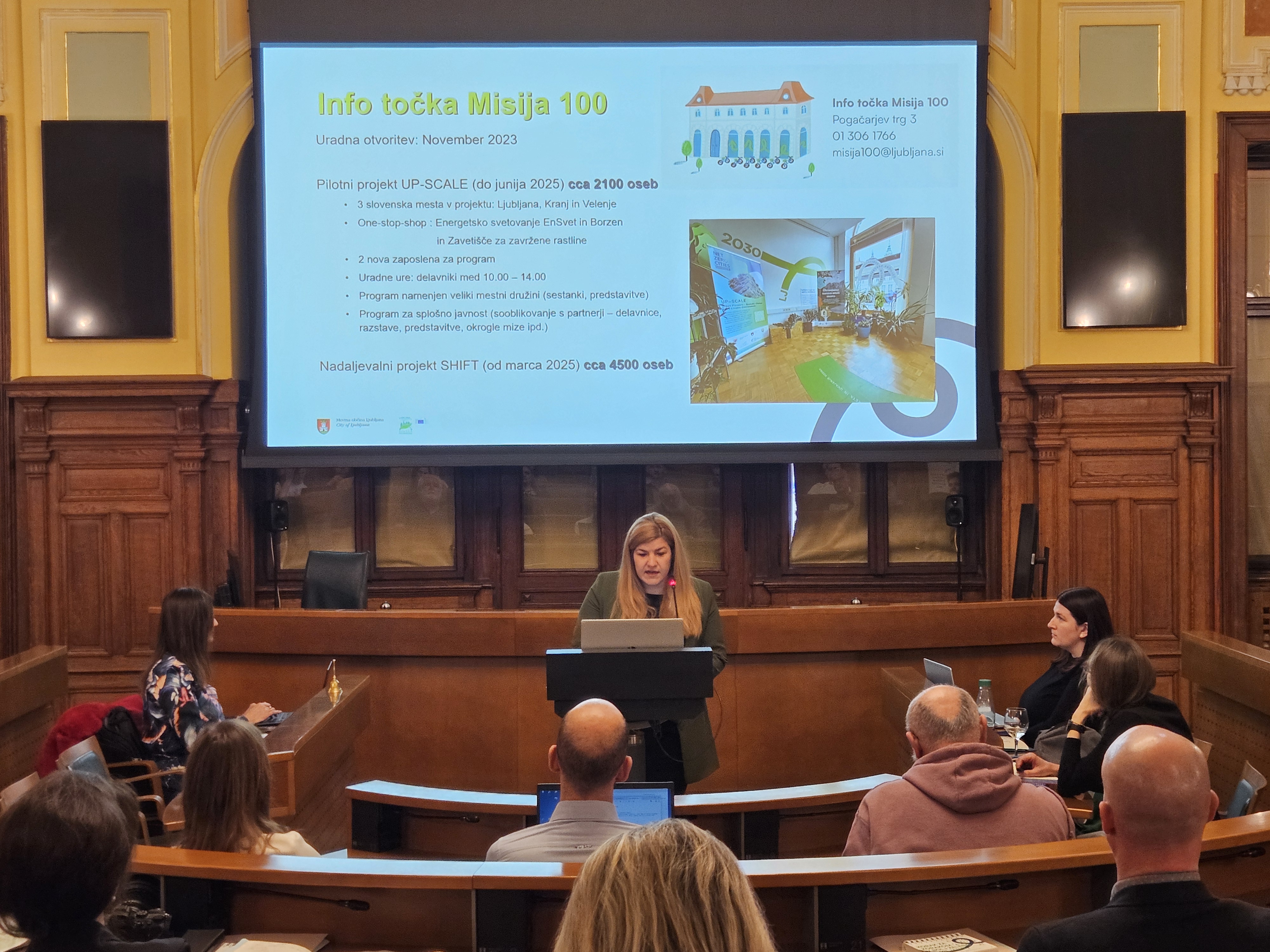 Lea Korva za govorniškim pultom, v ozadju prezentacija 