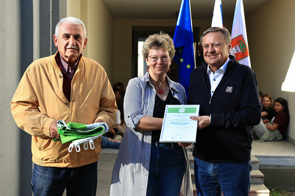 župan ter predstavnika stanovalcev s plaketo in zastavo v rokah