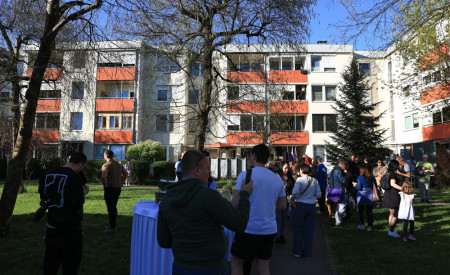 ljudje stojijo na zelenici pred blokom