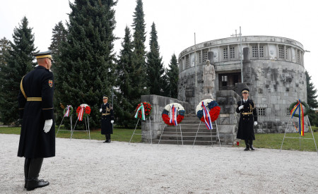 Slovesnost polaganja vencev pri Kostnici z vojaki v uniformah in vencih pred stavbo, obdano z drevesi.