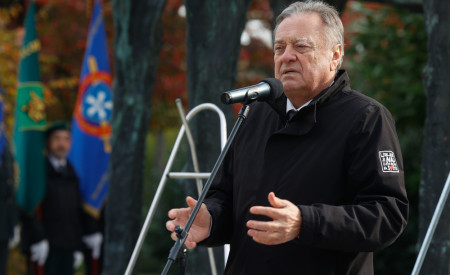 Župan Zoran Janković med govorom v spominskem parku padlih borcev in talcev s praporoma in uniformirani stražarji v ozadju.