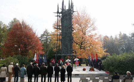 Udeleženci polagajo vence pri spomeniku v Spominskem parku padlih borcev in talcev. Jesensko obarvano drevje v ozadju.