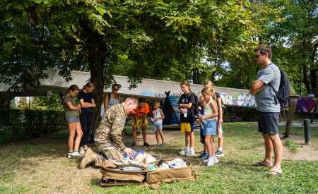 Pripadnik slovenske vojske obiskovalcem kaže prvo pomoč na lutki