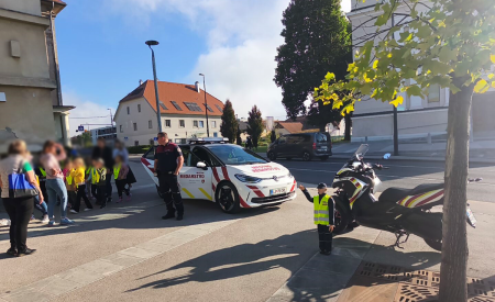 redarj stoji pred avtomobilom in se pogovarja z otroci