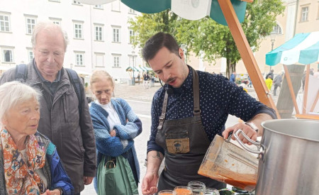 kuhar toči napitek v kozarce, obiskovalci opazujejo