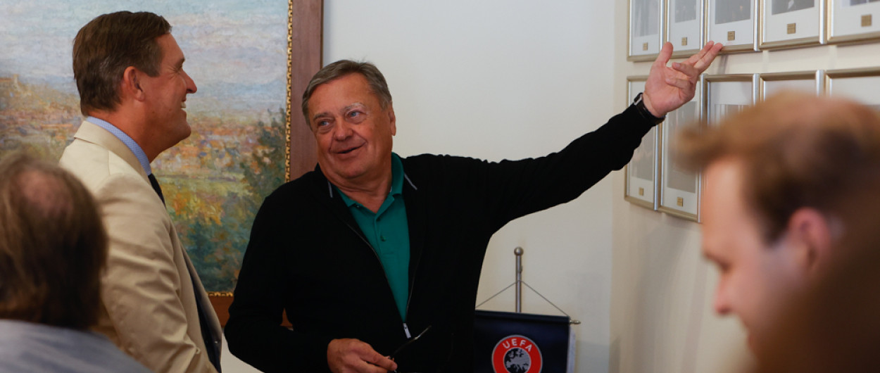 župan in mestni minister med pogovorom ob fotografijah na steni