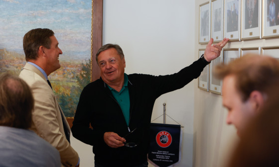 župan in mestni minister med pogovorom ob fotografijah na steni