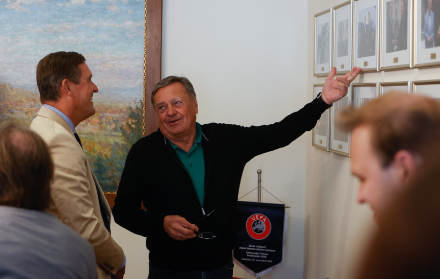 župan in mestni minister med pogovorom ob fotografijah na steni