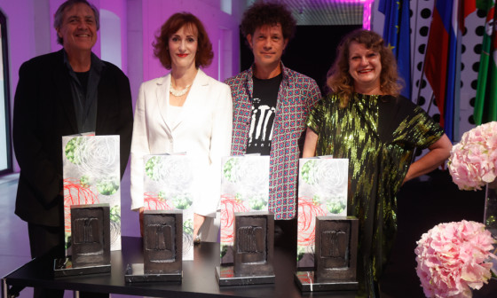 nagrajenci stojijo pred plaketami