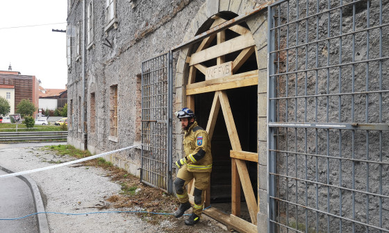 gasilec stopa iz delno porušene zgradbe