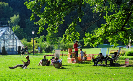 Knjižnica pod krošnjami z rastlinjakom v ozadju, foto: D. Wedam, vir Turizem Ljubljana