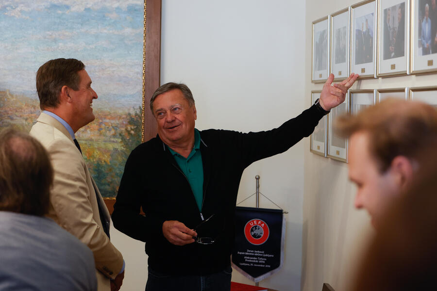 župan in mestni minister med pogovorom ob fotografijah na steni