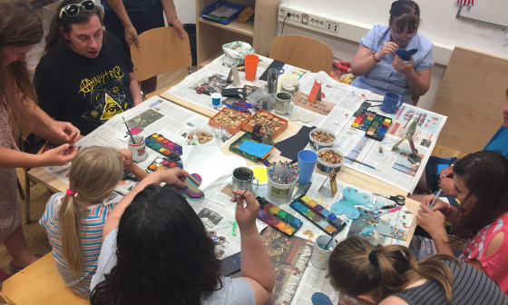 mladi sedijo okoli mize in ustvarjajo