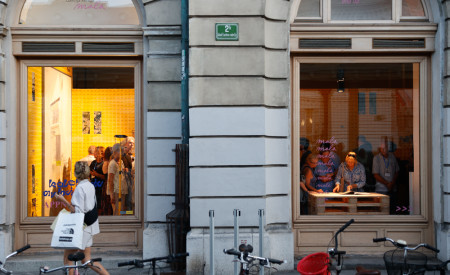 Veliak okna Galerije Kresija mala skozi katera se vidijo obiskovalci in razstava